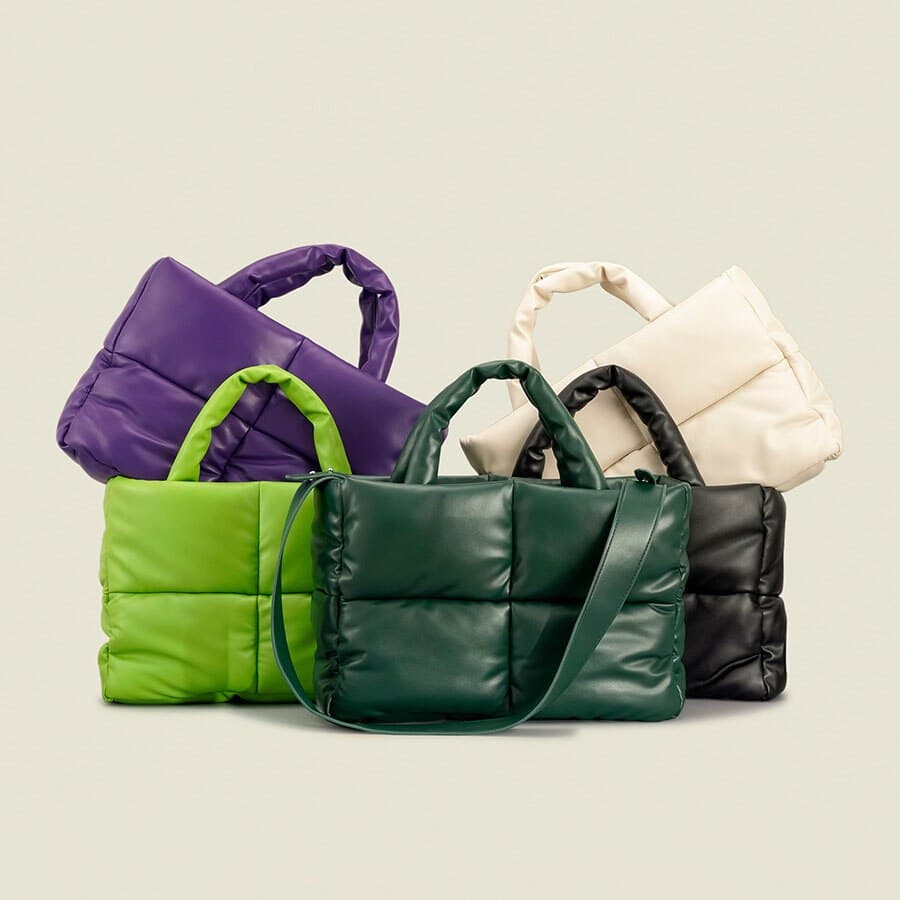 Plusieurs sacs à main de voyage rembourrés pour femmes, 3 sont présentés de face (vert clair, vert foncé, et noir, et 2 autres sont avec un coin mis dans l'un des premiers sacs, ceux des extrémités (un modèle violet et l'autre blanc)