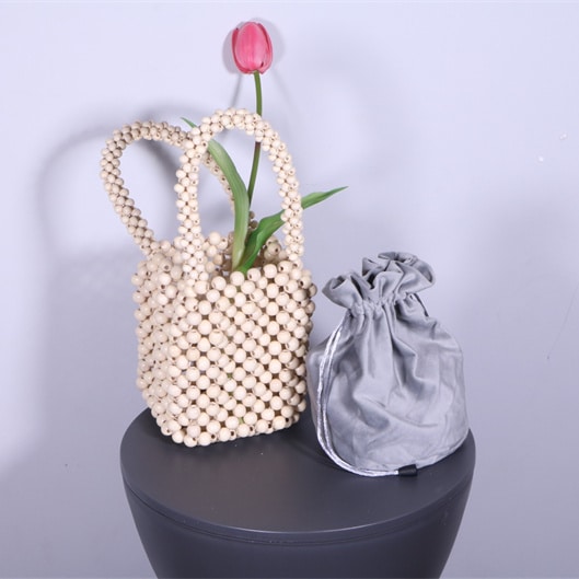 Petit sac à main perlé vintage pour femmes posé sur une table à côté d'un sac gris