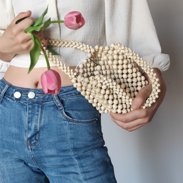 Femme le nombril à l'air avec une rose dans la main portant un petit sac à main perlé vintage pour femmes