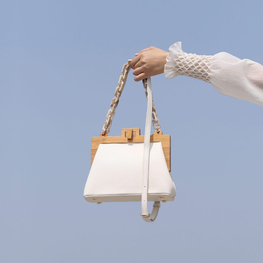 Main de femme qui tend un sac à main de luxe avec chaîne en acrylique pour femmes blanc