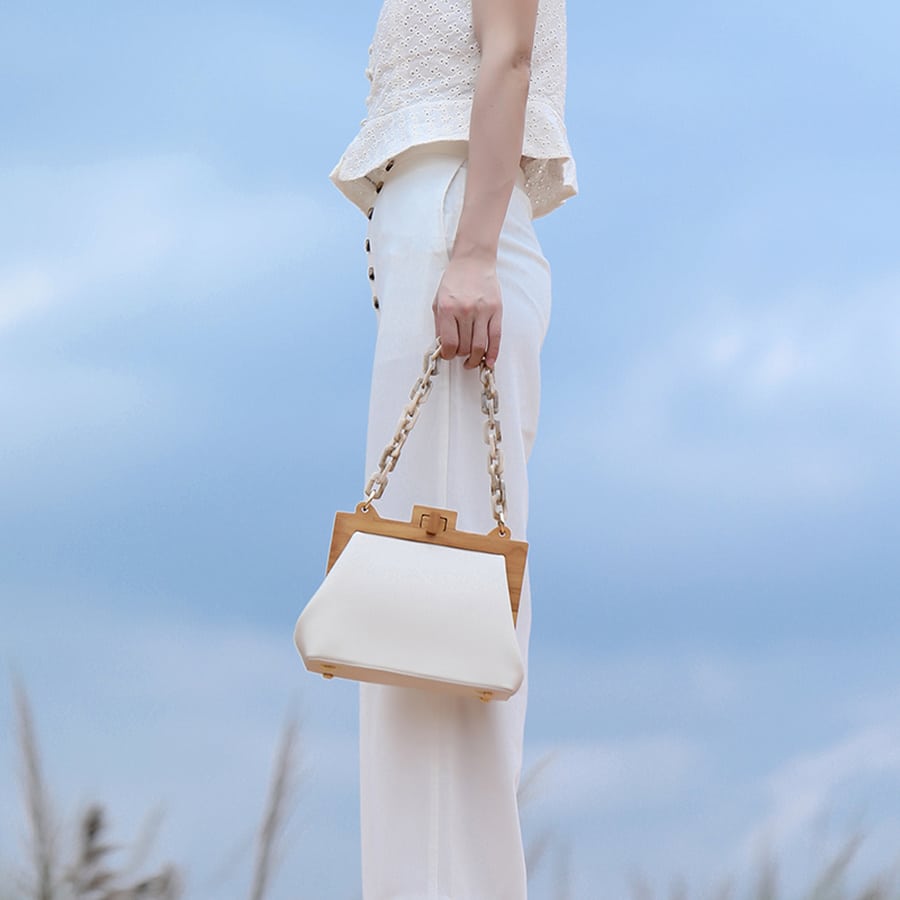 Femme de profil qui porte un sac à main de luxe avec chaîne en acrylique pour femmes blanc