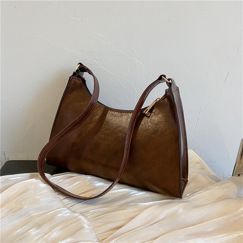 Petit sac à main marron façon cuir sur un fond blanc.