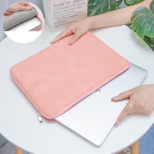 Pochette d'ordinateur posé sur une table, une main en train d'en sortir un ordinateur portable gris.