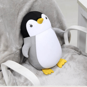 Coussin de Voyage en Forme de Pingouin en Polyester sur fond d'une chaise grise