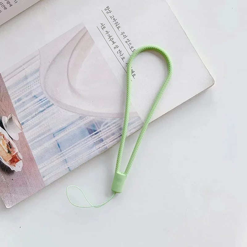 Bandoulière Téléphone Verte en Silicone sur fond blanc avec un livre