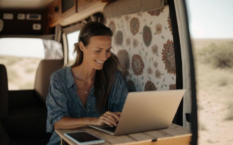 Femme dans un van, assise, utilisant un ordinateur portable sur une petite table.